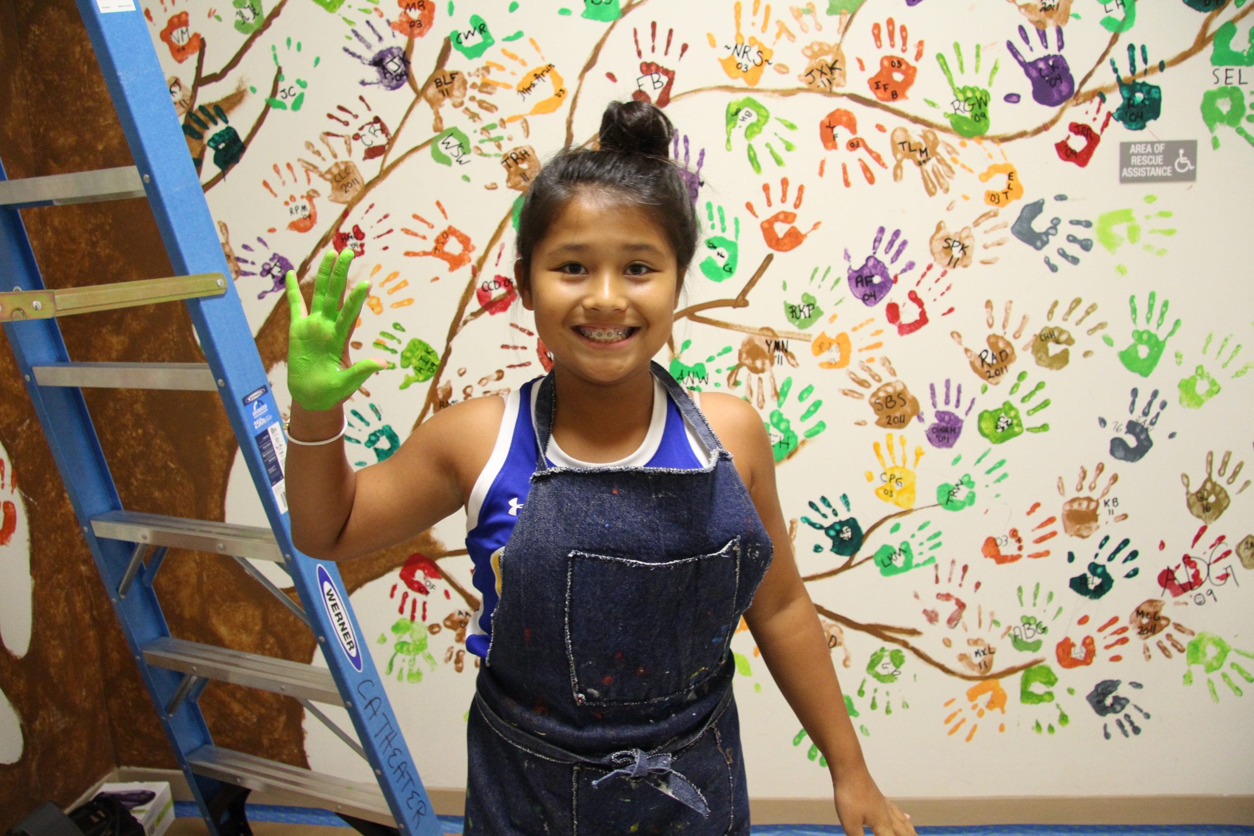 MS student in front of handprint mural